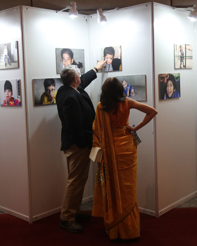 En man och en kvinna i Sari på en fotoutställning. Mannen pekar på ett barns ögon.