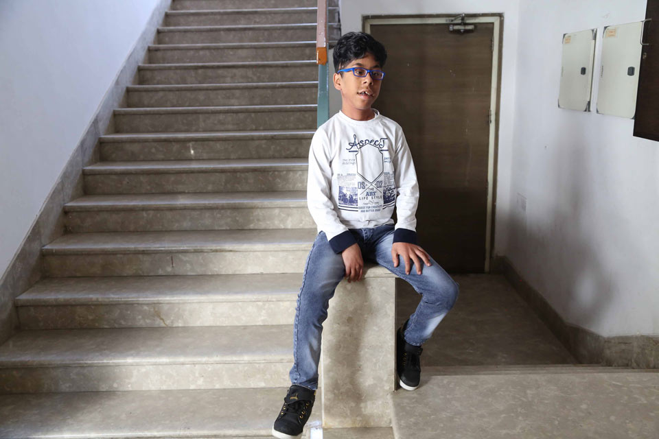 Pojke sitter på en mur med en trappa bakom honom.